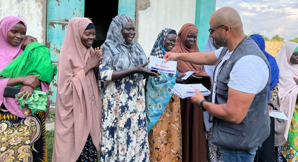 Uomo distribuisce buste della Zakat a donne in Africa.