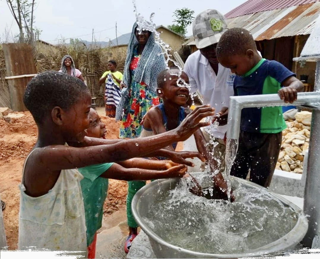 Enfants jouant avec l’eau d’un puits communautaire en Afrique