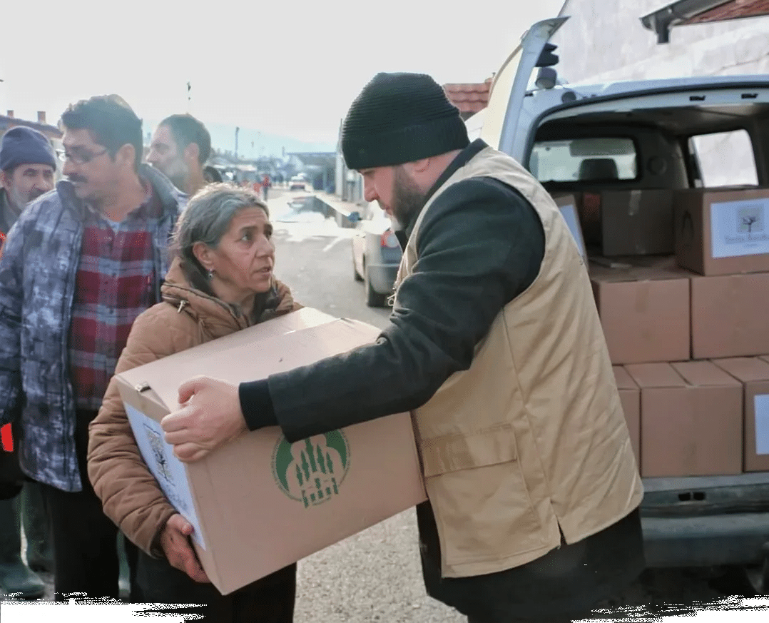 Un cooperant remet un carton de fournitures de secours d'urgence à une femme au Kosovo.