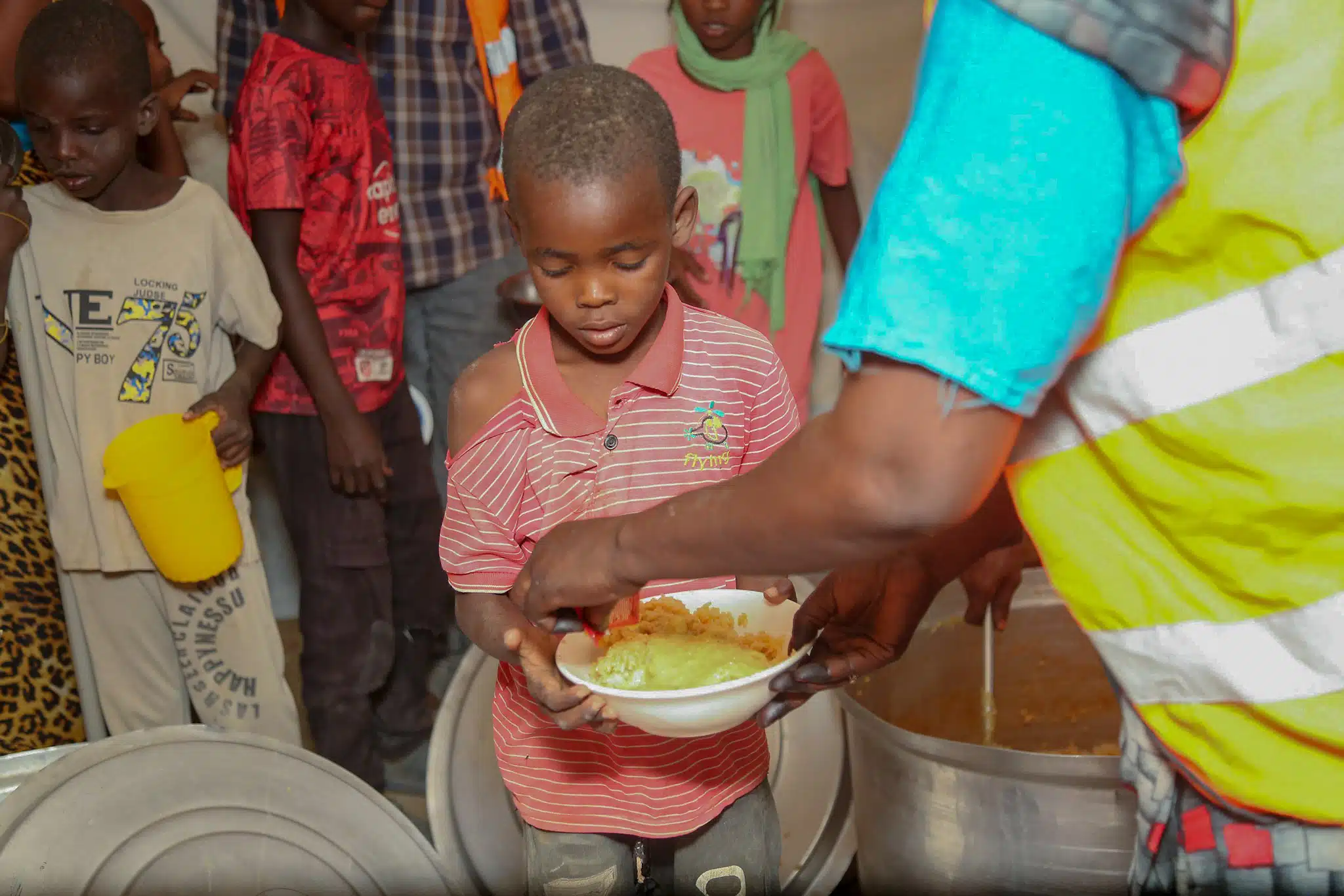 Un travailleur de Barakah Charity sert un repas chaud à un jeune garçon au Soudan.