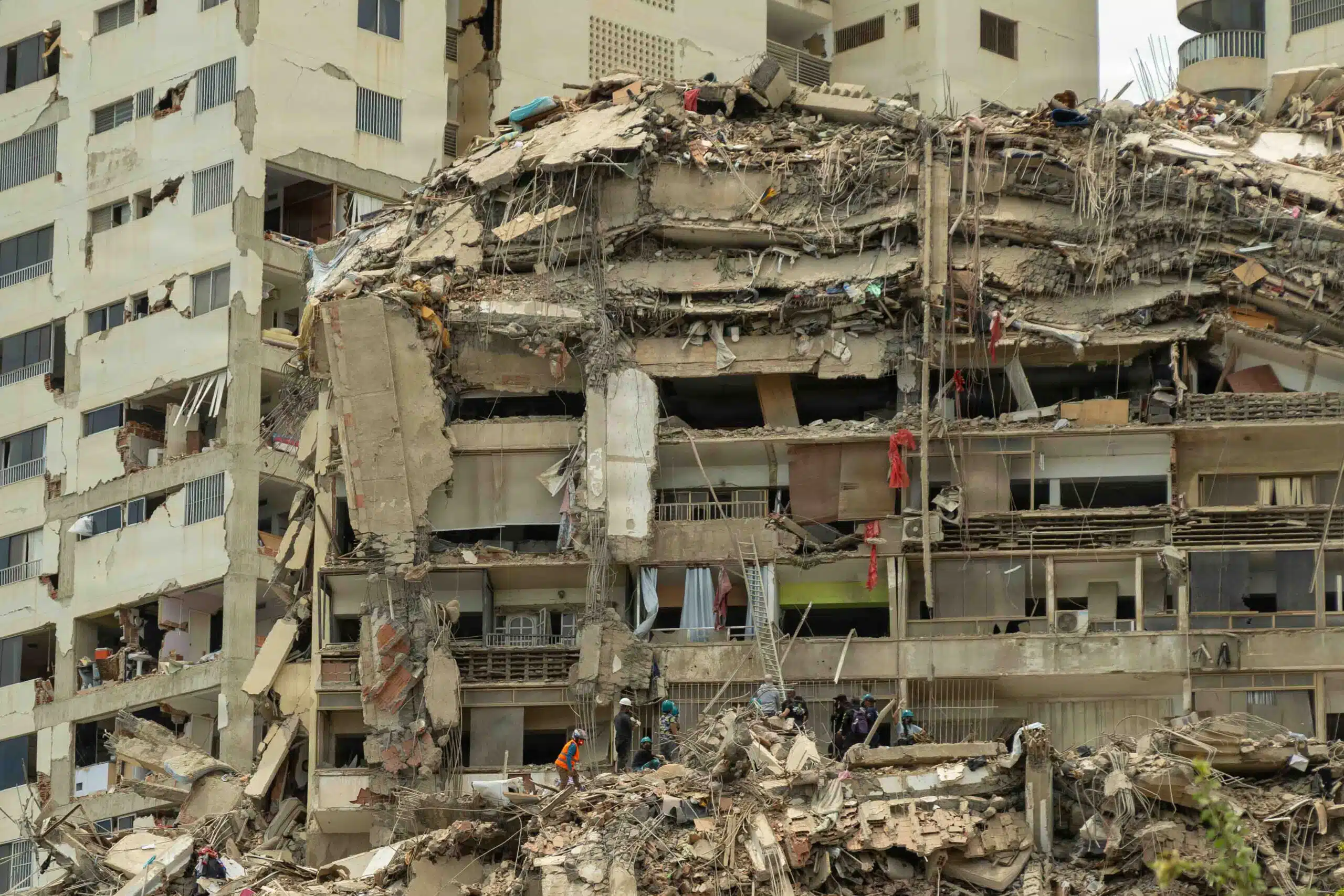 Rescue workers searching through the massive rubble of a heavily collapsed multi-story residential building following an earthquake in Venezuela.